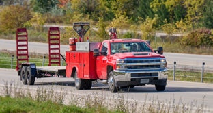 Utility pickup truck with landscaping equipment towing a trailer