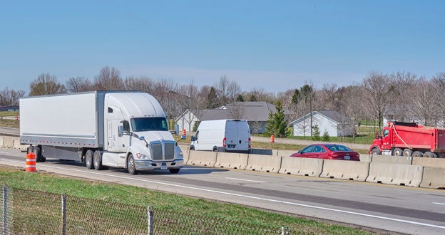 tractor trailer semi on divided highway with transport, sedan and dump truck