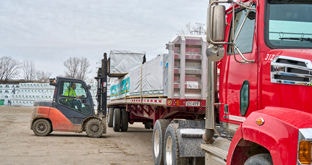 Tractor Semi with flatbed trailer being unloaded by forklift