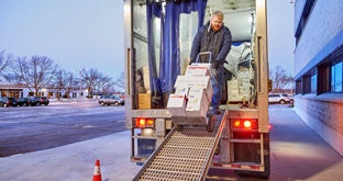 Person unloading a truck with boxes on a dolly going down a ramp