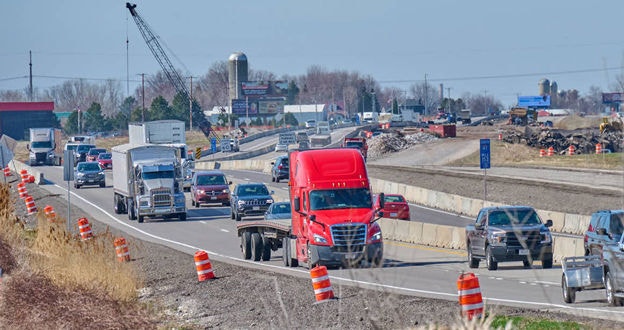 Heavy highway traffic of large trucks and cars in construction zone