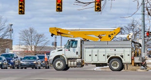 Utility truck with a bucket lift crossing a busy city intersection