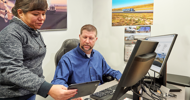 manager and driver at desk reviewing video on device