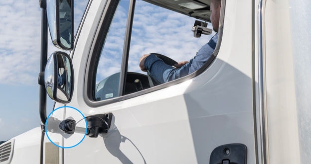 person driving semi truck with dash cam mounted to the windshield and side cam mounted to outside driver's side mirror mount
