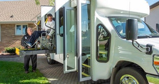 Driver aide assisting a person in a wheelchair into a medical transit vehicle