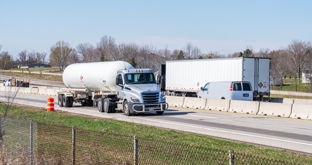 Divided highway with fuel tanker truck, commercial fleet van and semi with enclosed trailer
