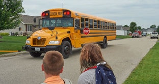 School bus stopped waiting for children to safely cross to the other side of the streee in residential area